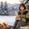 バルトロライトジャケットを着て、雪の積もった冬のキャンプ場で、温かい飲み物を手にくつろいでいる