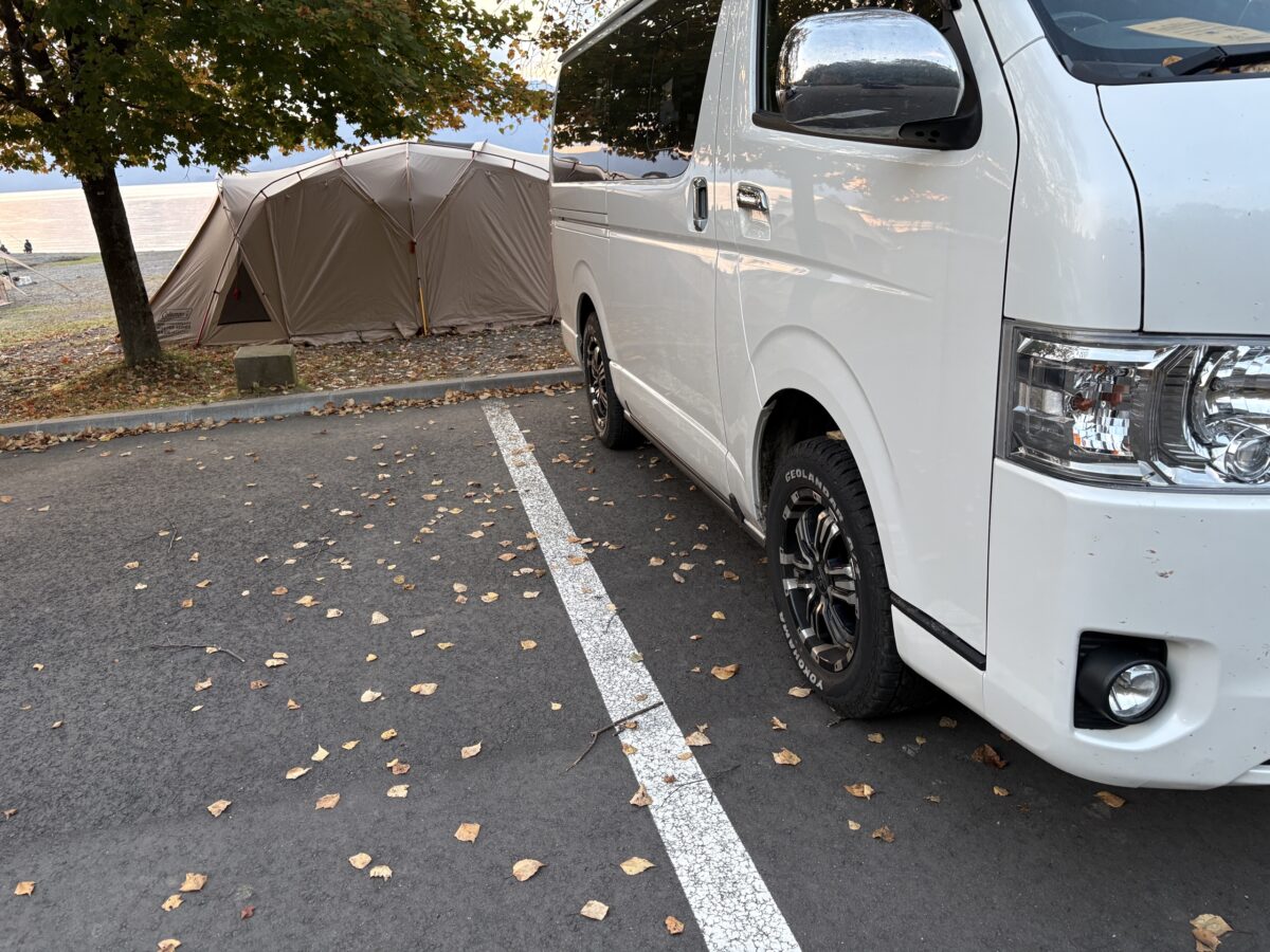 落ち葉の積もった秋のキャンプ場に停めたハイエース