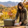 秋の湖のほとりで、テントの前の食材やゴミをていねいに片付けている