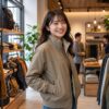 秋、おしゃれなアパレルショップの店内で、コンパクトノマドブルゾンを羽織ってうれしそうにしている