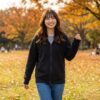 リアビューフルジップフーディを着て、秋の芝生の公園で楽しそうに散歩している