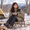 マウンテンダウンジャケットを着て、雪の残る冬のキャンプ場でくつろいでいる