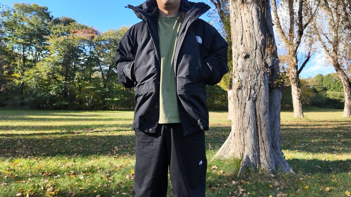 フリースベストを連結したマウンテンライトジャケットを秋の公園で着ているところ
